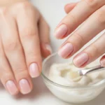 Zadbana dłoń z naturalnie lśniącymi paznokciami po zabiegu manicure japońskiego przy miseczce z pastą odżywczą.