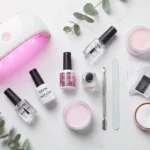 Zestaw do przedłużania paznokci: lampa UV/LED, żel budujący, bazy, szablony i akcesoria do manicure na jasnym tle.